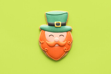 Tasty decorative gingerbread cookie for St. Patrick's Day celebration on green background