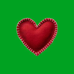 Handmade soft felt heart isolated on green background