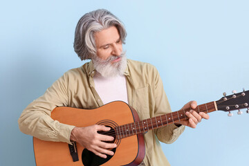 Fototapeta premium Bearded senior man playing guitar on blue background