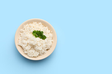Bowl with tasty boiled rice on blue background