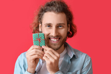 Happy young man with Christmas cookie on red background