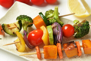 Plate with tasty vegetable skewers on table, closeup