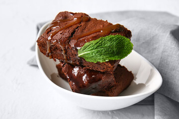 Bowl with pieces of tasty chocolate brownie on white background