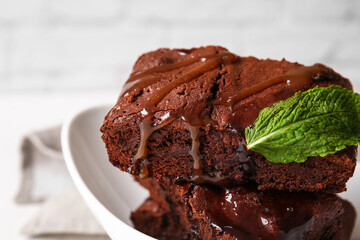 Bowl with pieces of tasty chocolate brownie on table, closeup