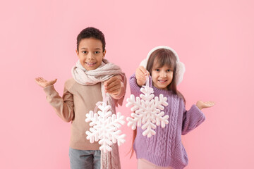Cute little children in winter sweaters and with snowflakes on color background