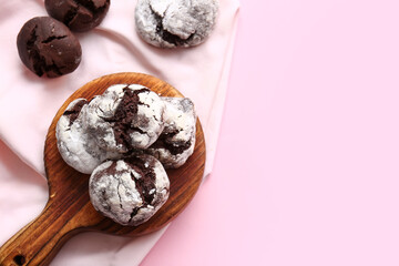 Board with tasty brownie cookies on pink background