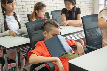 high school student sleeping with a book on his head in the classroom,Students feel bored and lazy...