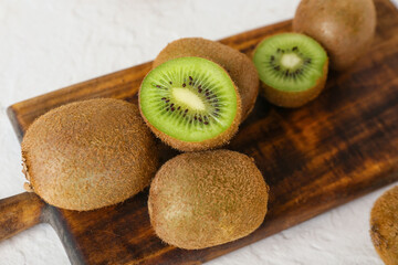 Board with fresh ripe kiwi on light background, closeup