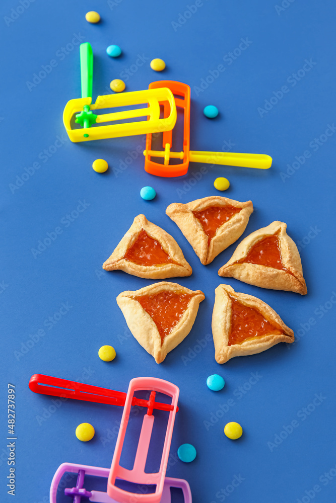 Wall mural Hamantaschen cookies and rattles for Purim holiday on color background