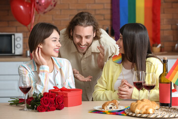 Man and two beautiful women celebrating Valentine's Day at home. Concept of polyamory and LGBT