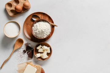 Bowl with flour and ingredients for preparing chocolate brownie on white background