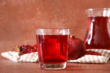 Glass of delicious pomegranate juice on brown background