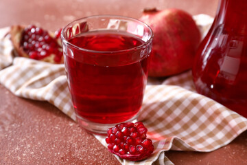 Glass of delicious pomegranate juice on brown background