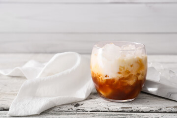 Glass of White Russian cocktail on light wooden background