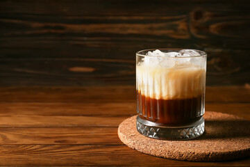 Glass of White Russian cocktail on wooden background