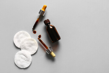 Bottle with iodine, pipettes and cotton pads on grey background