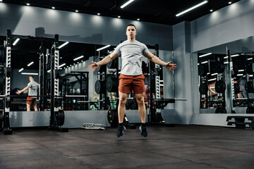 A strong sportsman doing jumping jacks in a gym. Fitness and gym workout.