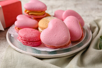 Plate with tasty heart-shaped macaroons on light background, closeup