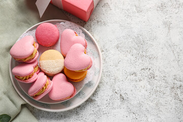 Plate with tasty heart-shaped macaroons on light background