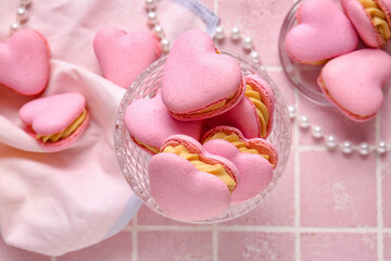 Dessert bowl with tasty heart-shaped macaroons on pink background, closeup