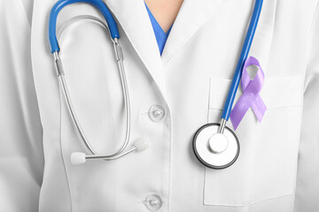 Female doctor with lavender awareness ribbon, closeup. World Cancer Day