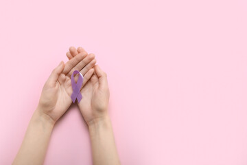 Female hands with lavender awareness ribbon on color background. World Cancer Day