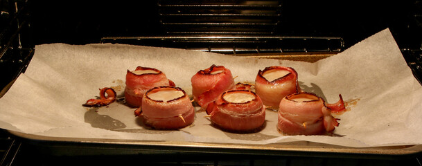 Large scallops wrapped in bacon cooking in the oven.