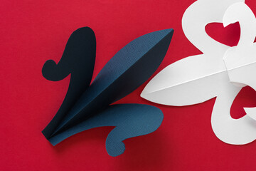 blue and white stylized lily (also fleur de lys) on a red paper surface