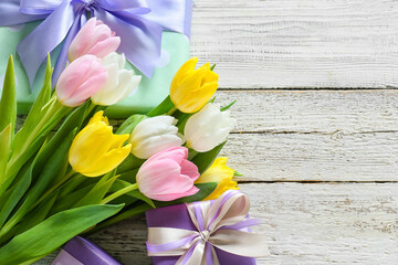 Composition with gift boxes and flowers for International Women's Day celebration on light wooden background, closeup