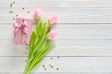 Composition with gift box and flowers for International Women's Day celebration on light wooden background