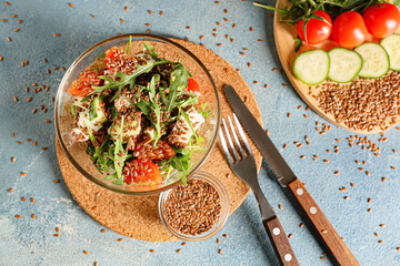 Bowl with healthy vegetable salad flax seeds on color background