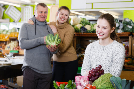 Portrait of satisfied tweenage girl during family shopping in fruit store