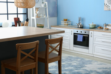 Bar counter and wooden chairs in light modern kitchen