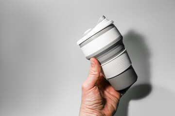 Reusable silicone cup for coffee in hand on a white background.
