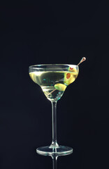 Martini cocktail with olives on dark background, space for text