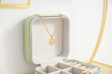 Jewelry box with stylish necklace near light wall, closeup