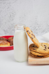 Galletas de chocolate con vaso de leche  sobre tabla de madera