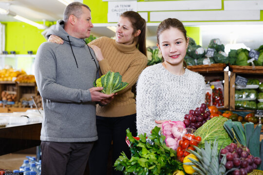 Portrait of satisfied tweenage girl during family shopping in fruit store