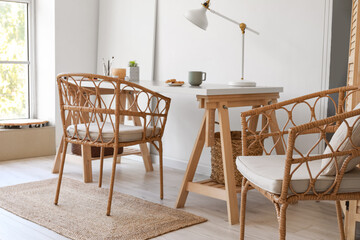Wooden table and wicker chairs in interior of light room