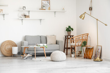 Interior of light living room with grey sofa and wicker chair