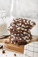 Wooden board of tasty cookies with white chocolate chips on table