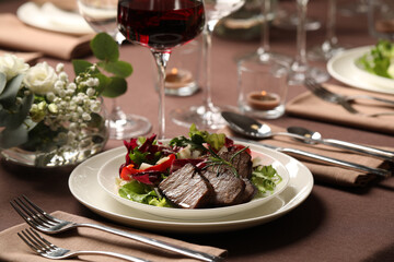 Delicious grilled meat with vegetables and wine served on table in restaurant