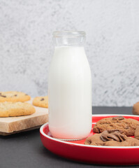 Galletas de chocolate con vaso de leche sobre plato rojo 