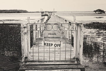warning sign to keep out, no trespassing, locked gate to jetty, black and white monochrome