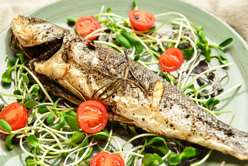 Plate with sea bass fish, microgreens and tomatoes, closeup