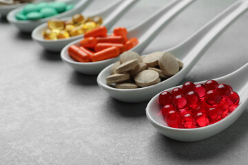 Spoons with different dietary supplements on light grey table, closeup. Space for text