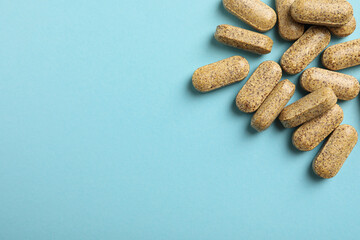Dietary supplement pills on light blue background, flat lay. Space for text