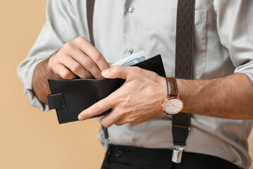 Fashionable gentleman holding opened wallet on color background, closeup