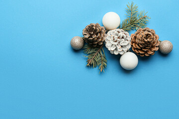 Fototapeta na wymiar Composition with pine cones, Christmas balls and fir branches on blue background