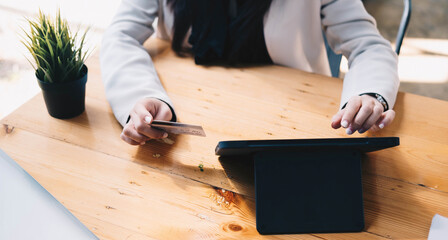 Online payment,woman's hands holding a credit card and using laptop computer for online shopping with vintage filter tone
